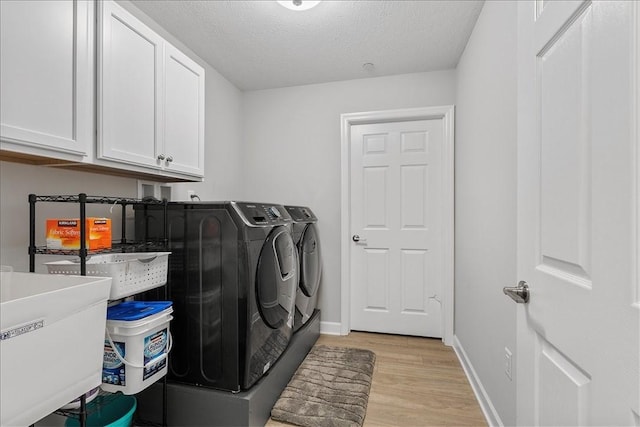 103 Spring Valley Dr, Jackson Twp, PA 16063 - laundry area featuring washing machine and dryer, cabinet space, light wood finished floors, and a textured ceiling