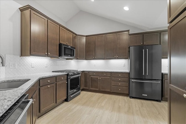 103 Spring Valley Dr, Jackson Twp, PA 16063 - kitchen featuring premium appliances, light stone countertops, vaulted ceiling, light wood-style flooring, and tasteful backsplash