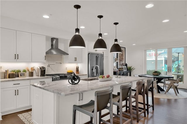 1817 Fox Way S, Side, PA 15203 - kitchen featuring wall chimney range hood, appliances with stainless steel finishes, tasteful backsplash, a kitchen island with sink, and white cabinets