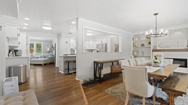 8609 Peters Rd, Cranberry Twp, PA 16066 - dining space with a chandelier, dark wood-type flooring, recessed lighting, crown molding, and a glass covered fireplace