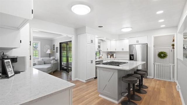 8609 Peters Rd, Cranberry Twp, PA 16066 - kitchen with stainless steel fridge, gas stovetop, white cabinetry, a breakfast bar, and light wood-style floors