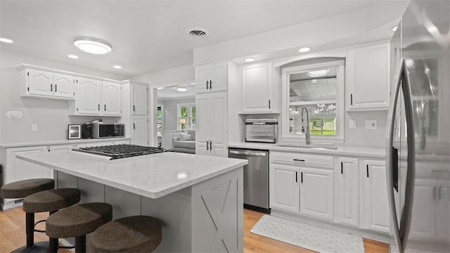 8609 Peters Rd, Cranberry Twp, PA 16066 - kitchen with stainless steel appliances, a breakfast bar area, light wood-style floors, a center island, and white cabinetry