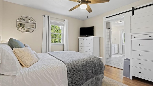 8609 Peters Rd, Cranberry Twp, PA 16066 - bedroom with wood finished floors, a barn door, ensuite bathroom, and a ceiling fan