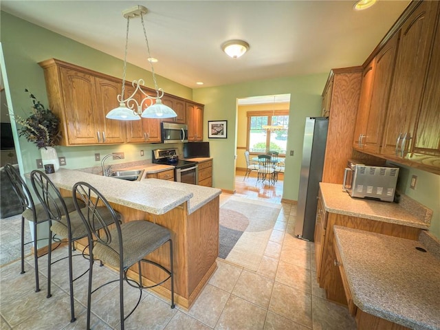 121 Covington Dr, Center Twp, PA 16001 - kitchen featuring stainless steel appliances, a peninsula, a kitchen breakfast bar, brown cabinetry, and pendant lighting