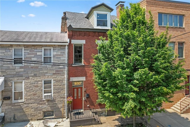 160 45th St, Lawrenceville, PA 15201 - view of front facade featuring stone siding, cooling unit, and a chimney