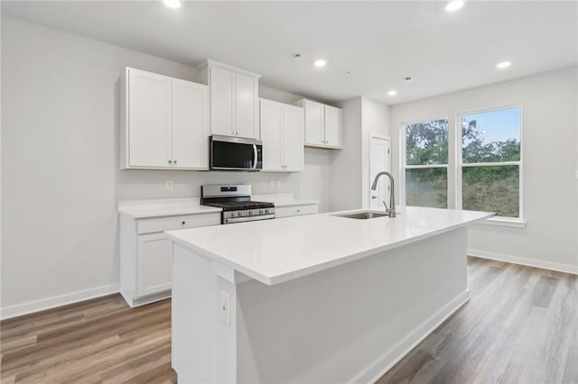 116 River Ridge Drive, Moon/Crescent Twp, PA 15108 - kitchen featuring appliances with stainless steel finishes, a center island with sink, white cabinetry, light wood-type flooring, and light countertops