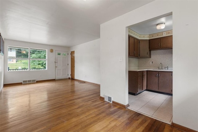 809 Sleepy Hollow Rd, Castle Shannon, PA 15234 - kitchen featuring light countertops, light wood-style floors, tasteful backsplash, dark brown cabinets, and open floor plan