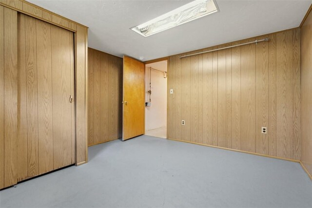 809 Sleepy Hollow Rd, Castle Shannon, PA 15234 - unfurnished bedroom featuring wooden walls, finished concrete flooring, and a closet