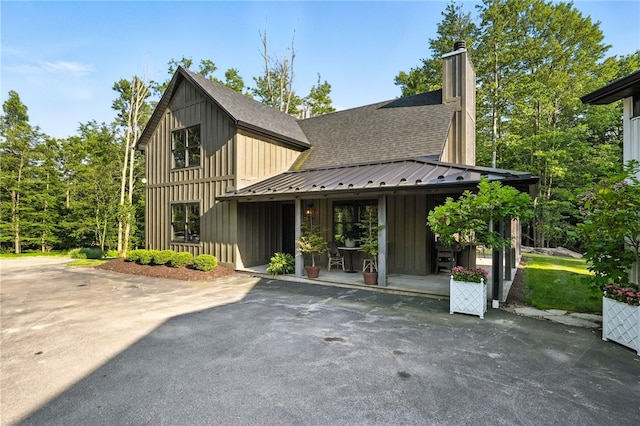 50 Hawes Rd, Wharton Twp, PA 15437 - view of front of home with board and batten siding, roof with shingles, a chimney, asphalt driveway, and a patio