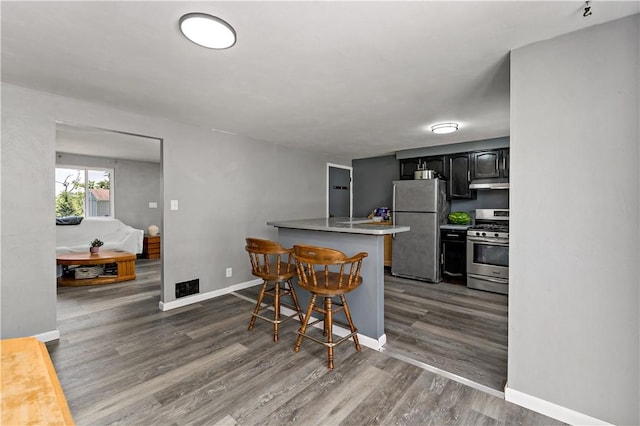 553 Indus St, Greenfield, PA 15207 - kitchen featuring stainless steel appliances, a kitchen bar, wood finished floors, a peninsula, and under cabinet range hood