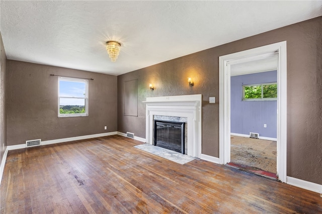 1000 Prospect Rd, Whitehall, PA 15227 - unfurnished living room with healthy amount of natural light, wood finished floors, a high end fireplace, and a textured wall