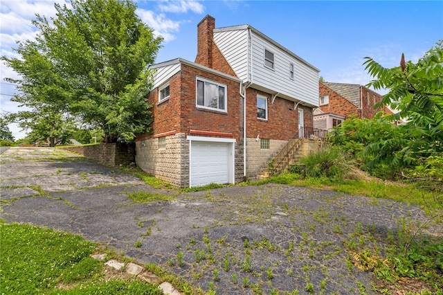 1000 Prospect Rd, Whitehall, PA 15227 - view of home's exterior with an attached garage, asphalt driveway, stairs, and a chimney
