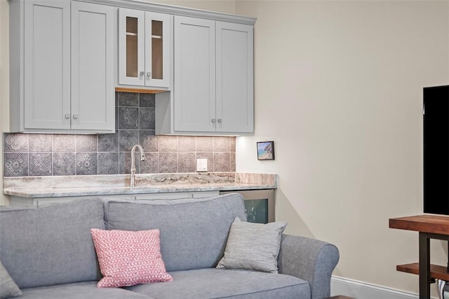 246 42nd St, Lawrenceville, PA 15201 - kitchen featuring backsplash, glass insert cabinets, and light stone countertops
