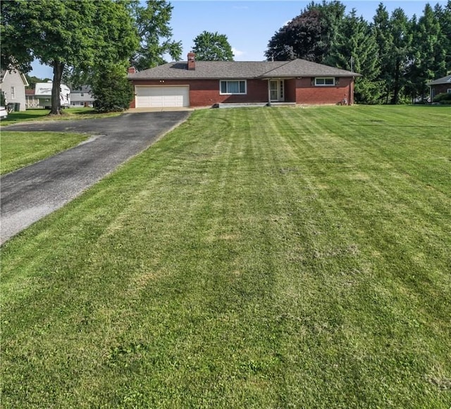 single story home with asphalt driveway, a chimney, brick siding, and an attached garage
