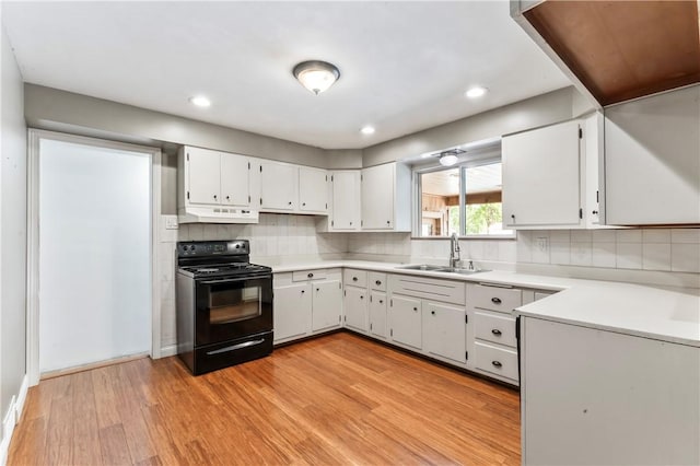 kitchen featuring black range with electric cooktop, under cabinet range hood, light wood-type flooring, light countertops, and white cabinetry