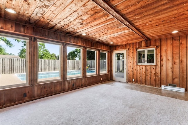 unfurnished sunroom with wood ceiling, healthy amount of natural light, wooden walls, and carpet