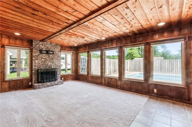 unfurnished living room featuring wood ceiling, wood walls, healthy amount of natural light, a fireplace, and tile patterned floors