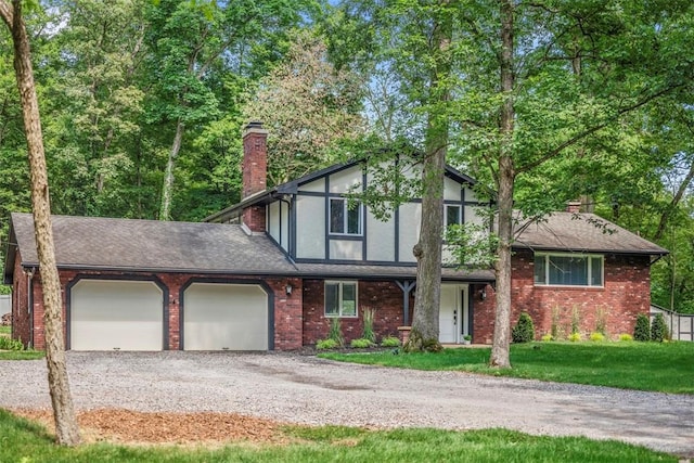 124 Heath Dr, Economy, PA 15005 - tudor house with a chimney, gravel driveway, a garage, a front yard, and brick siding
