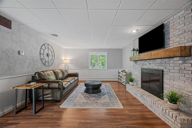 124 Heath Dr, Economy, PA 15005 - living area with a baseboard radiator, a fireplace, a drop ceiling, wood finished floors, and a wainscoted wall