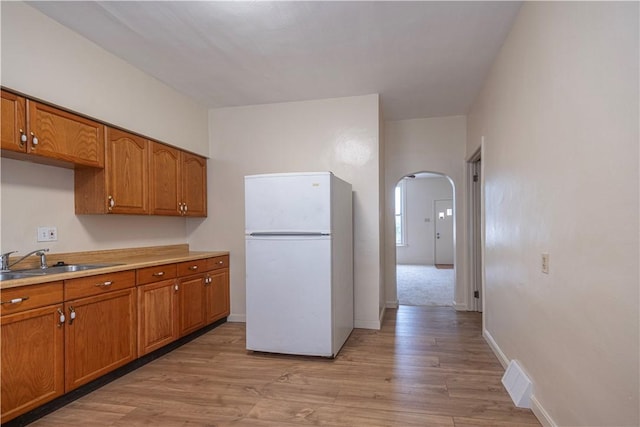 3240 Rothpletz St, Marshall Shadeland, PA 15212 - kitchen featuring freestanding refrigerator, brown cabinets, arched walkways, and light wood-style floors