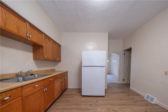 3240 Rothpletz St, Marshall Shadeland, PA 15212 - kitchen with freestanding refrigerator, arched walkways, light wood-style floors, brown cabinetry, and light countertops