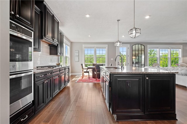 1735 Stevensan Dr, Franklin Park, PA 15143 - kitchen with stainless steel appliances, dark cabinets, wood finished floors, backsplash, and light stone countertops
