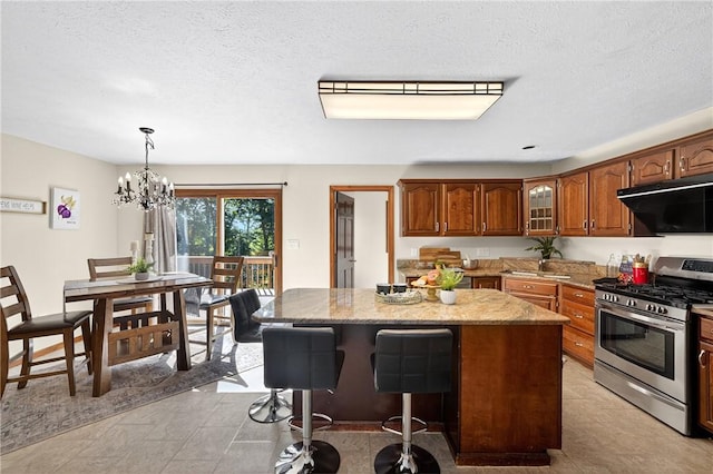 2455 Dogwood Dr, Franklin Park, PA 15090 - kitchen featuring gas stove, range hood, a kitchen island, light stone counters, and brown cabinetry