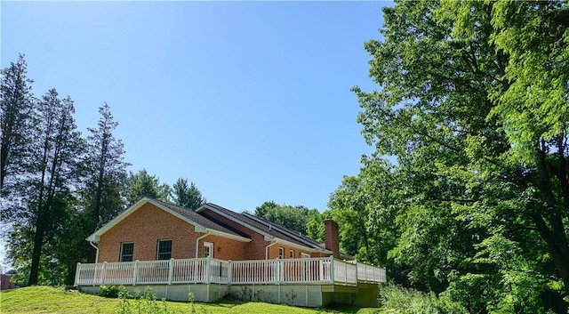 1664 N Main St, Center Twp, PA 16001 - view of home's exterior featuring brick siding, a lawn, a deck, and a chimney
