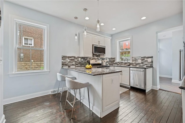 4228 Post St, Lawrenceville, PA 15201 - kitchen featuring stainless steel appliances, white cabinets, backsplash, a breakfast bar area, and a peninsula