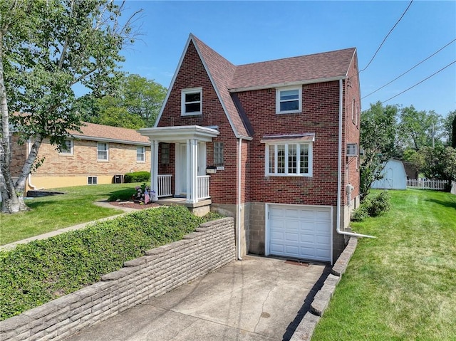 1445 Stanley Dr, Penn Hills, PA 15147 - tudor house featuring concrete driveway, a garage, brick siding, a front yard, and a shingled roof