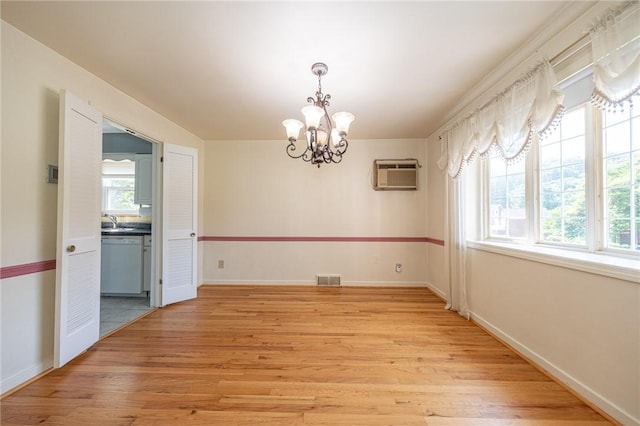1445 Stanley Dr, Penn Hills, PA 15147 - unfurnished room featuring a wall unit AC, a chandelier, and light wood-style flooring