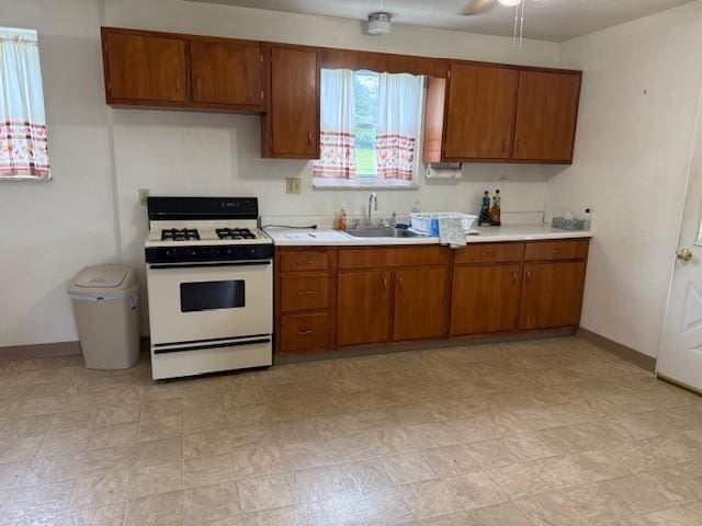410 Hershey Rd, Penn Hills, PA 15235 - kitchen with gas range gas stove, brown cabinetry, light countertops, a ceiling fan, and light flooring