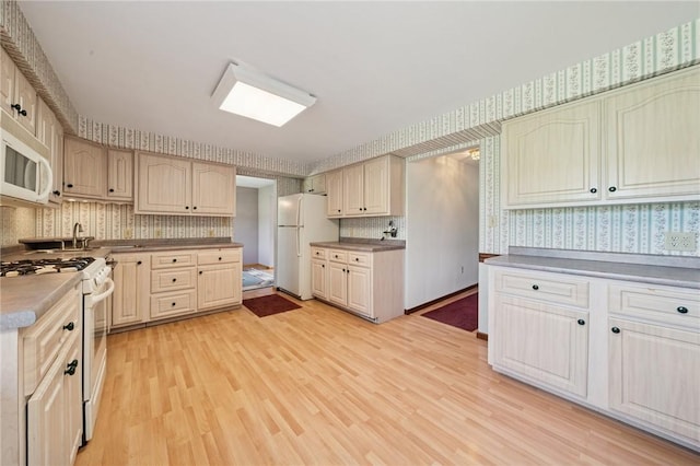 318 E Edgewood Ave, Trafford, PA 15085 - kitchen featuring white appliances, light wood finished floors, wallpapered walls, and decorative backsplash
