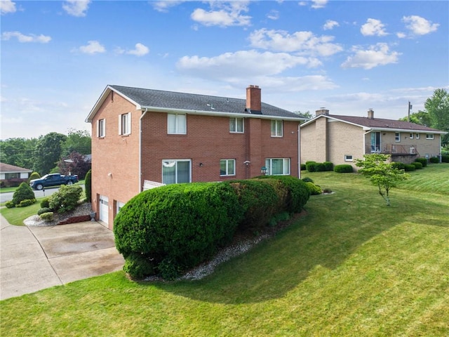 145 Herbst Rd, Kennedy Twp, PA 15108 - rear view of house with concrete driveway, a chimney, an attached garage, brick siding, and a lawn
