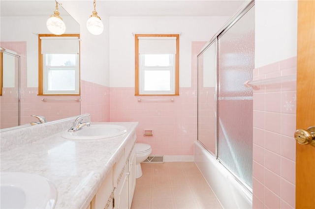 125 Jackson St, White Twp, PA 15701 - full bathroom featuring tile walls, plenty of natural light, double vanity, a wainscoted wall, and combined bath / shower with glass door