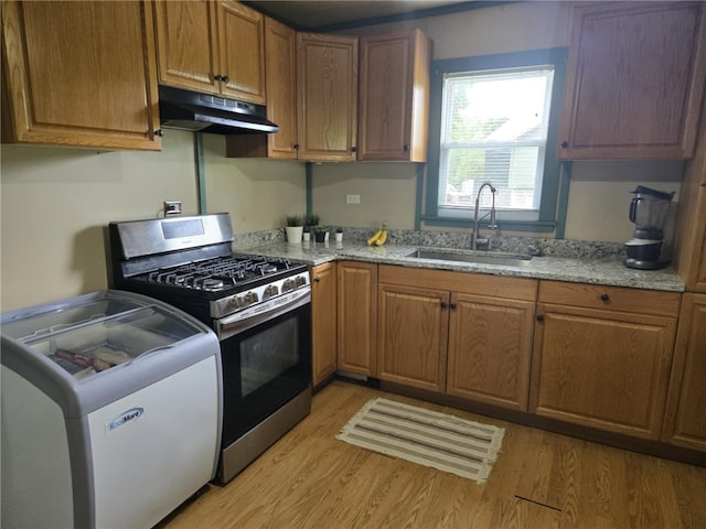 223 Park Ave, Bruin Boro, PA 16022 - kitchen with stainless steel range with gas stovetop, under cabinet range hood, washer / clothes dryer, light wood-style flooring, and light stone countertops