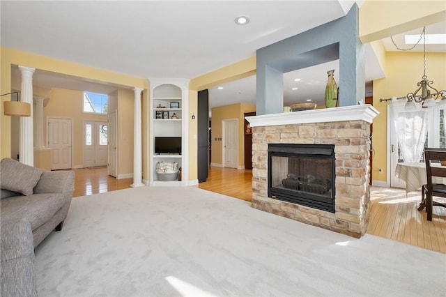 1100 Eleanor Pl, Adams Twp, PA 15044 - living area with wood finished floors, a stone fireplace, built in shelves, ornate columns, and recessed lighting