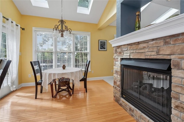 1100 Eleanor Pl, Adams Twp, PA 15044 - dining space with a skylight, light wood finished floors, a chandelier, vaulted ceiling, and a stone fireplace