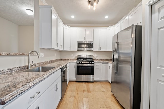 212 Olivia Dr, Plum Boro, PA 15068 - kitchen with appliances with stainless steel finishes, light wood finished floors, light stone countertops, white cabinetry, and a textured ceiling