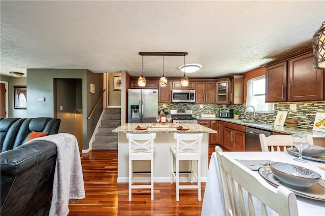 221 Wheatfield Dr, Hempfield Twp, PA 15601 - kitchen with appliances with stainless steel finishes, a textured ceiling, open floor plan, decorative backsplash, and a kitchen breakfast bar