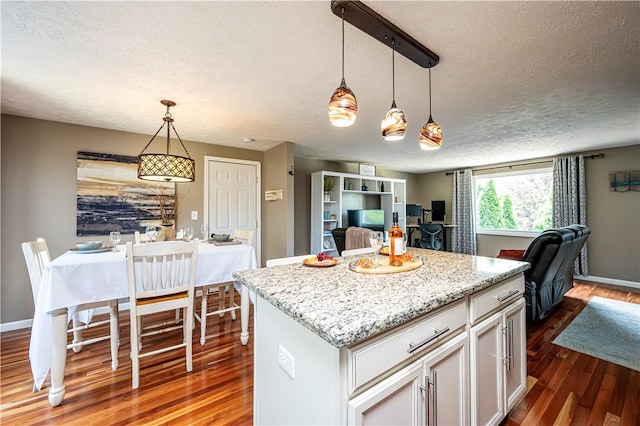 221 Wheatfield Dr, Hempfield Twp, PA 15601 - kitchen with a textured ceiling, open floor plan, dark wood finished floors, a kitchen island, and decorative light fixtures