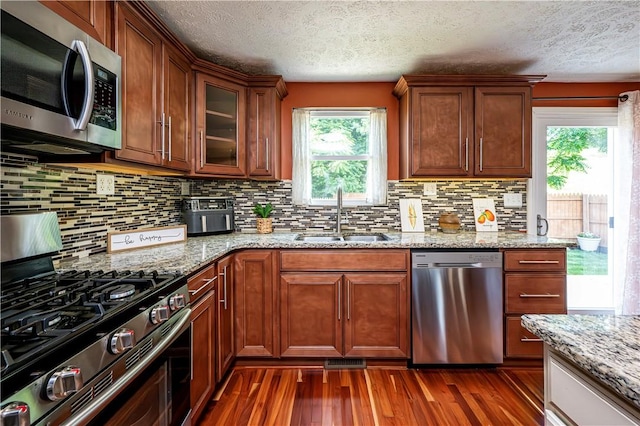 221 Wheatfield Dr, Hempfield Twp, PA 15601 - kitchen with stainless steel appliances, healthy amount of natural light, a textured ceiling, dark wood finished floors, and decorative backsplash