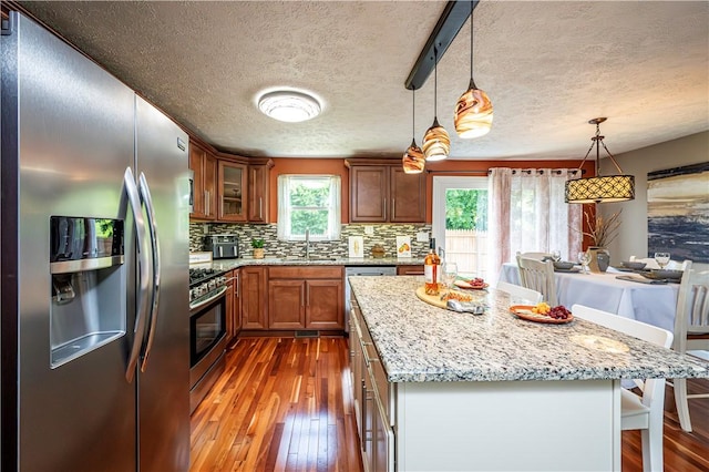221 Wheatfield Dr, Hempfield Twp, PA 15601 - kitchen featuring stainless steel appliances, dark wood-style floors, a breakfast bar, backsplash, and a textured ceiling