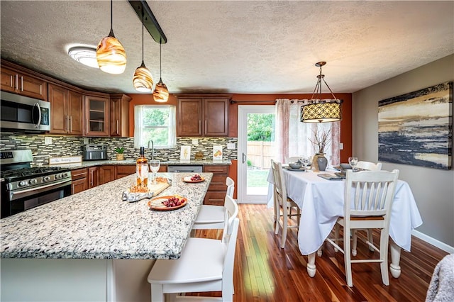 221 Wheatfield Dr, Hempfield Twp, PA 15601 - kitchen with stainless steel appliances, plenty of natural light, backsplash, wood finished floors, and a textured ceiling