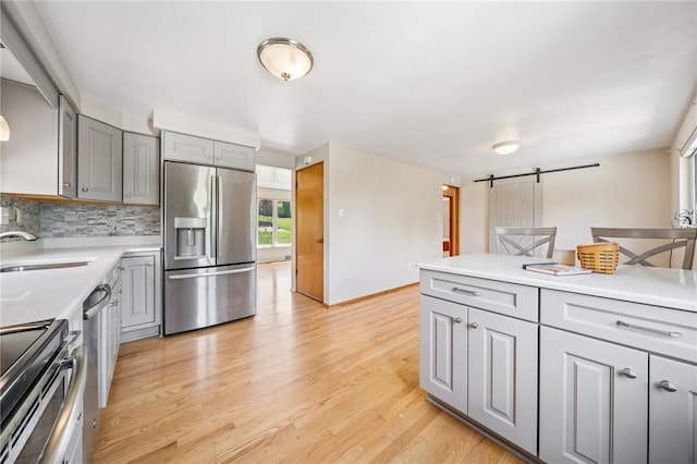 1533 Missouri Ave, South Park, PA 15017 - kitchen with stainless steel appliances, gray cabinetry, a barn door, tasteful backsplash, and light wood-style flooring
