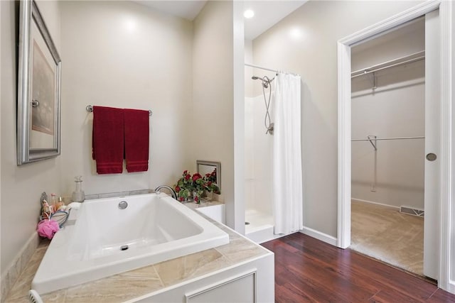 202 Ringneck Meadow Dr, Worth Twp, PA 16057 - bathroom with a bath, a walk in closet, a shower with shower curtain, and wood finished floors