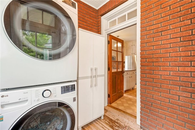 429 S Center Ave, Somerset Boro, PA 15501 - laundry room featuring stacked washing machine and dryer, cabinet space, brick wall, and light wood-style floors
