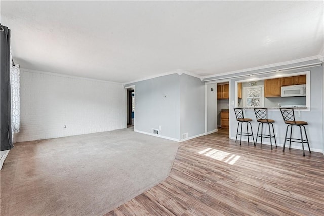 339 Foster Rd N, Versailles, PA 15137 - unfurnished living room with crown molding, light wood-style floors, and brick wall