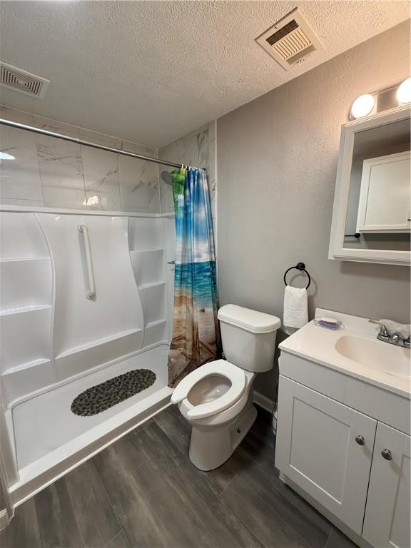 6028 Davidson Rd, Jamestown, PA 16134 - full bath with a textured ceiling, vanity, a shower stall, wood finished floors, and a textured wall