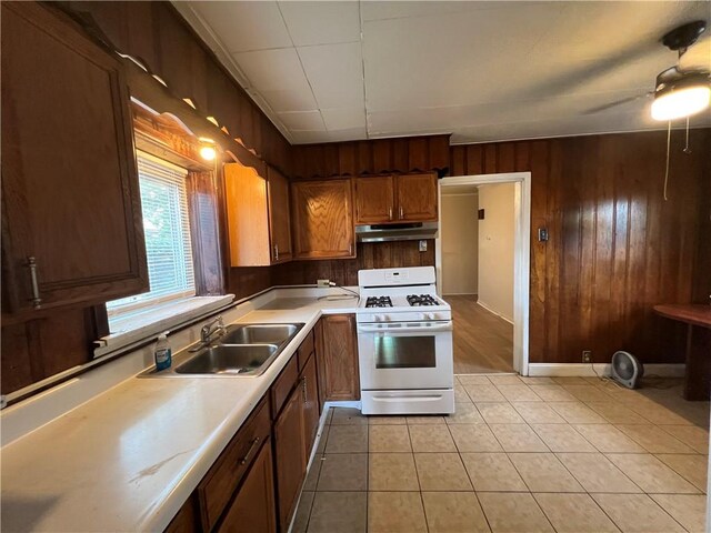 2220 Cronemeyer St, Mckeesport, PA 15132 - kitchen with white gas range, under cabinet range hood, wood walls, light countertops, and light tile patterned floors